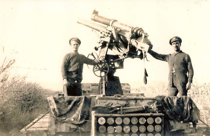 two soldiers standing by anti aircraft gun